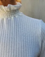 Polera de manga larga en tejido acanalado color blanco, con cuello alto y puños con detalle de punto smock fruncido.