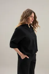 Camisa de lino de calce relajado, color negro, con cuello mao, mangas cortas y bajo redondeado con aberturas laterales.