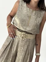 Conjunto de musculosa y pantalón palazzo color dorado brillante. La musculosa es sin mangas y el pantalón es de corte ancho con cintura alta.