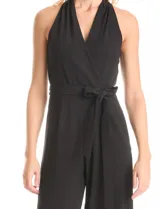 Enterito largo negro de crepe, con escote en V cruzado, sin mangas y lazo de ajuste en la cintura. Presenta bolsillos verticales en la parte delantera y una abertura en forma de gota con broches de gancho y cierre invisible en la espalda.