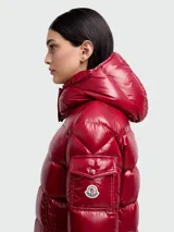 Campera puffer de nylon brillante en color rojo, con capucha desmontable, cierre frontal y bolsillos laterales. Presenta un diseño acolchado horizontal y logo de la marca en la manga.