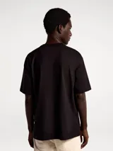 Camiseta de manga corta en tejido de punto texturizado con diseño de rayas verticales sutiles, cuello redondo y corte holgado.