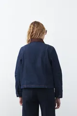 Campera de jean color negro con cuello de pana en tono marrón, cierre frontal con botones metálicos y bolsillos frontales tipo cargo.