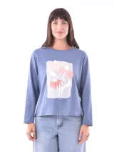 Remera de manga larga color azul, con cuello redondo y un estampado central de flores en tonos pastel sobre un recuadro gris claro.
