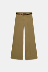 Jeans de tiro alto color tostado, con cinco bolsillos, pernera ancha y detalle de nervio marcado en el delantero. Incluye un cinturón fino de cuero marrón con textura de cocodrilo y hebilla dorada. Cierre frontal con cremallera y botón.