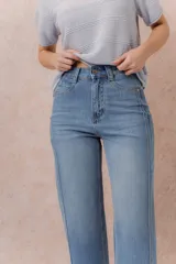 Jean de denim celeste con lavado claro, corte recto y tiro medio-alto, con diseño de cinco bolsillos y cierre frontal con botón y cremallera.