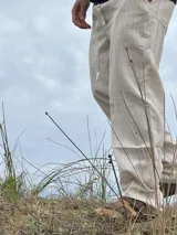 Pantalón de lino beige y crudo a rayas, de corte ancho y relajado.