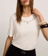 Remera blanca de viscosa con cuello redondo, mangas cortas y apliques de strass en el cuello.