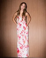 Vestido largo con estampado tie-dye en tonos fucsia, rojo y blanco, de corte ajustado, con escote tipo buche y tirantes finos.