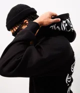 Buzo canguro negro Blue Steel de fleece con capucha, manga larga y cierre frontal. Cuenta con lettering bordado en la capucha y un diseño circular estampado en la espalda en color blanco con tipografía gótica.