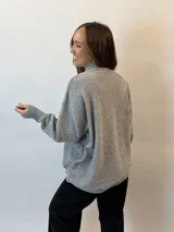 Buzo gris melange de tejido de punto, con cuello alto redondo, mangas largas y corte holgado.