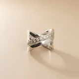 Anillo de diseño cruzado confeccionado en plata 925, con una banda central decorada con circonias engastadas y bandas laterales lisas de acabado pulido.