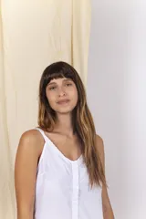 Musculosa de tela de camisa color amarillo claro, con escote en V decorado con detalles bordados, breteles finos y cierre frontal abotonado.