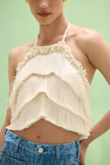Top halter color marfil con escote redondo, espalda descubierta y diseño de capas de flecos con apliques de perlas y cuentas en el cuello.