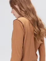 Polera de cuello alto confeccionada en tela rib color blanco, con mangas largas y hombreras. Presenta pespuntes en contraste en las terminaciones del cuello, hombros y puños.