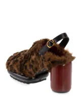 Sueco negro con pelo sintético, taco de madera y hebilla trasera para ajustar al talón.