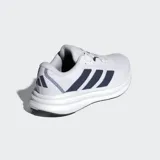 Championes de running Adidas modelo Galaxy 7, color blanco con las tres tiras laterales en azul marino. Presentan una mediasuela con tecnología Cloudfoam para mayor amortiguación y empeine textil transpirable.