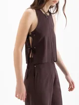 Top de twill color beige, de silueta recta y diseño sin mangas con cuello redondo. Se destaca por sus aberturas laterales con lazos regulables y remaches metálicos.