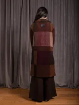 Chaquetón largo de paño con diseño de cuadros en tonos tierra, borravino y negro. Presenta cuello solapa, bolsillos laterales y forro interior.