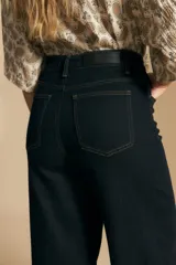 Jean de tiro alto y pierna ancha, confeccionado en denim azul oscuro con costuras a contratono. Presenta un diseño de corte recto y holgado.