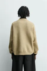 Jersey de punto con textura efecto pelo, corte relajado, cuello redondo y manga larga con acabados en rib.