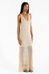 Vestido largo de punto abierto con sutil brillo dorado, escote en V y diseño sin mangas con detalles de flecos en el ruedo.