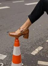 Zapato tipo Mary Jane de cuero vacuno color suela, con punta cuadrada, taco bloque y tira con hebilla metálica sobre el empeine.