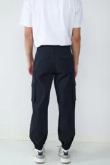 Pantalón cargo tipo jogger color negro, con bolsillos laterales con solapa, cintura con cierre y botón, y puños elásticos en los tobillos.