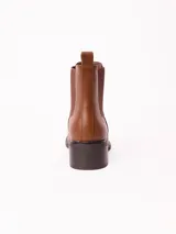 Bota tipo Chelsea color marrón, con paneles laterales elásticos, punta redondeada y taco cuadrado bajo.