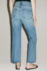 Jeans cropped flare de tiro medio color celeste, confeccionados en denim con efecto lavado. Presentan diseño de cinco bolsillos, trabillas para cinto, raya planchada al frente y bajo desflecado con terminación evasé. Cuenta con cierre frontal de cremallera y botón metálico.
