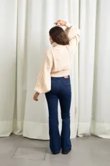 Polera de punto color manteca, con cuello alto, diseño de trenzas y flores en el frente, y mangas globo amplias.