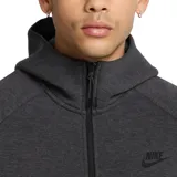 Campera deportiva Nike Tech Fleece con capucha, cierre frontal completo y bolsillo lateral con cierre termosellado en la manga izquierda. Presenta diseño ergonómico con costuras características de la línea Tech.