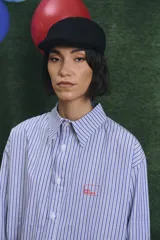 Camisa de corte oversize con estampado a rayas verticales en tonos azul y blanco, cuello clásico y cierre frontal con botones.
