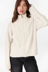 Campera de punto tejido color beige con diseño de ochos, cuello alto y cierre frontal completo.