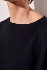 Sweater de tejido de punto en color negro, con corte oversize, cuello redondo y mangas largas con puños acanalados.