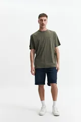 Remera de manga corta color gris claro, con cuello redondo y estampado pequeño en el pecho con texto en rojo y negro.