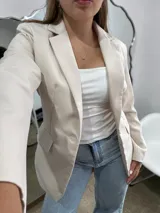 Blazer sastrero de corte clásico en color beige, con solapas tradicionales, cierre frontal de un botón y bolsillos laterales con solapa.
