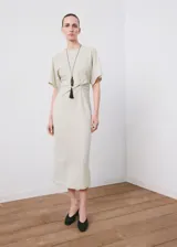 Vestido midi color beige claro, de corte recto, con cuello redondo, mangas cortas y detalle de frunce en la cintura.