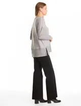 Buzo de calce suelto confeccionado en tejido melange de punto suave, con escote en V, mangas largas con hombros caídos y detalles de tejido rib en puños y ruedo. Presenta aberturas laterales y un diseño asimétrico con la parte posterior ligeramente más larga.