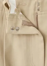 Pantalón de tiro medio color tostado, de corte recto y diseño largo con pinzas en la parte delantera y trabillas para cinturón. Cuenta con bolsillos laterales y cierre oculto.