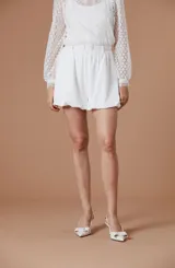 Short blanco de tiro alto, confeccionado en tela ligera, con diseño abuchonado y cinturón incorporado con hebilla forrada.