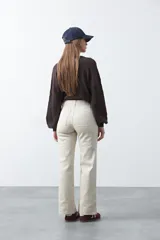Pantalón de mujer color beige, de corte recto y tiro alto, con costuras frontales marcadas que recorren la pierna.