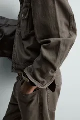Cazadora de denim de algodón en color gris oscuro con efecto lavado, corte relaxed fit, cuello camisero, bolsillos delanteros con solapa en el pecho y cierre frontal con botones.