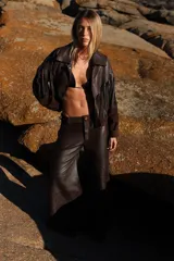 Pantalon de corte wide leg confeccionado en una combinación de cueros ovinos en tonos chocolate, incluyendo paneles de cuero liso, cuero desgastado y gamuza suave. Presenta diseño de cinco bolsillos y cierre frontal.