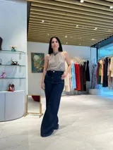 Jean de mezclilla azul oscuro, tiro alto, corte ancho y pierna acampanada. Presenta un diseño de talle alto con costuras frontales que simulan un cruce o doblez.