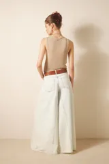 Jean de tiro alto y corte ultra ancho, confeccionado en denim rígido con lavado bleach que le otorga un tono casi blanco. Presenta recortes estratégicos en las piernas y el tiro, brindando una silueta con gran vuelo y movimiento. Incluye cierre y botón frontal, además de forrería interna estampada.