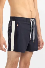 Short de baño azul marino con tira lateral blanca estilo tuxedo, cintura elástica con cordón regulable, dos bolsillos laterales y uno trasero con cierre.