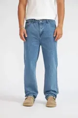 Pantalón jeans Quiksilver modelo Arno de corte recto y tiro medio, en tono azul medio con efecto desgastado. Cuenta con presillas para cinturón y bolsillos clásicos.