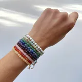 Set de pulseras elásticas elaboradas con mini cuentas de piedras naturales de 4 mm de diámetro, con nudo corredizo ajustable. Incluye una variedad de piedras como howlita, cuarzo rosa, jade, cornalina, cuarzo verde, amazonita, lepidolita, ojo de buey y cuarzo azul.