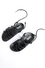 Sandalias bajas negras de cuero con tiras tubulares entrecruzadas y pulsera tobillera.